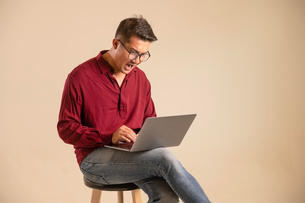 Simple young freelancer sitting working on laptop pc computer looking isolated on bright colored wall studio photo background