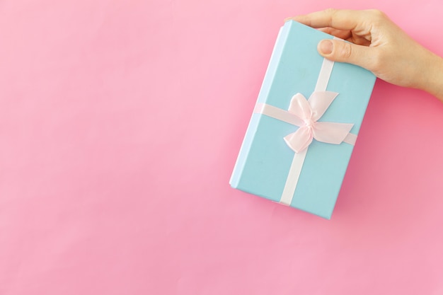 Просто дизайн женская женщина рука синей подарочной коробке, изолированных на розовом пастельных красочных модный фон