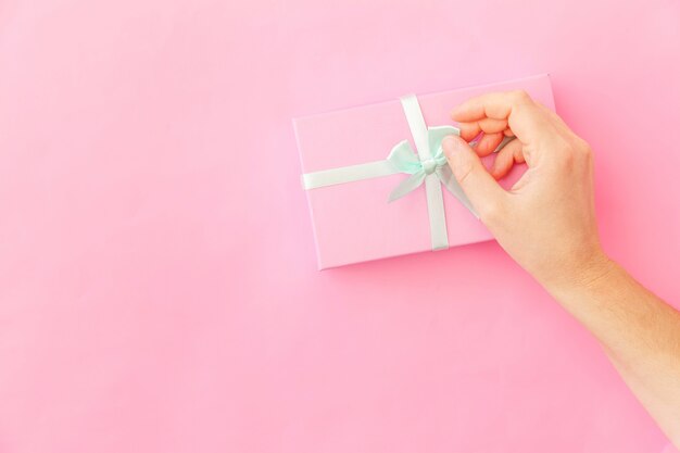 Simply design female woman hand holding pink gift box isolated on pink pastel colorful trendy background