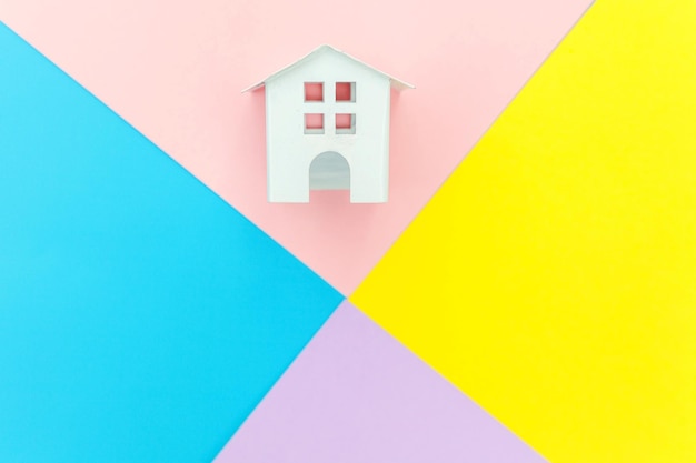 Photo simply design miniature white toy house isolated on blue yellow pink purple pastel colorful trendy g...