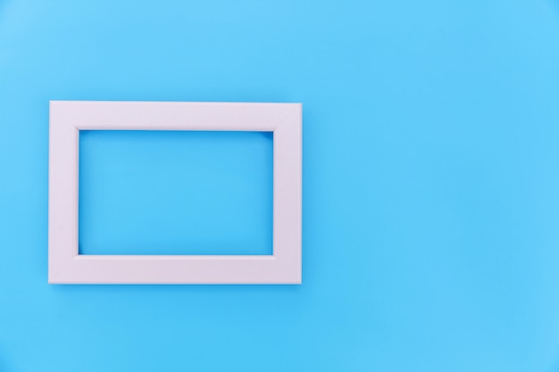 Simply design with empty pink frame isolated on blue pastel colorful background. Top view, flat lay, copy space, mock up. Minimal concept.