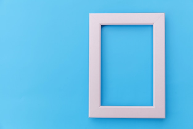 Simply design with empty pink frame isolated on blue pastel colorful background. Top view, flat lay, copy space, mock up. Minimal concept.