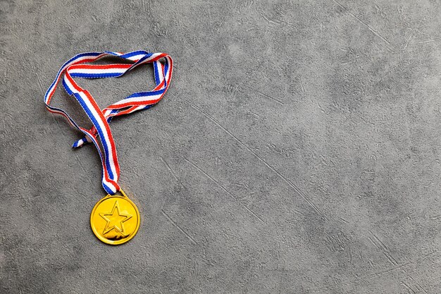 Simply flat lay design winner or champion gold trophy medal on concrete stone grey background Victory first place of competition Winning or success concept Top view flat lay copy space