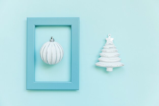 Simply minimal composition winter objects ornament fir tree ball in blue frame isolated on blue pastel trendy background. Christmas New Year december time for celebration concept. Flat lay top view