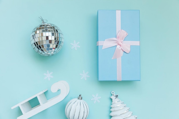 Simply minimal composition winter objects ornament sled fir tree ball gift box isolated blue pastel background. Christmas New Year december time for celebration concept. Flat lay top view copy space