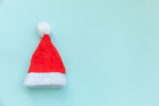 Simply minimal design Christmas Santa Claus hat isolated on blue pastel colorful trendy background. Christmas New Year december time for celebration concept. Flat lay top view copy space