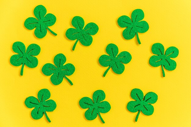 Simply minimal design with green shamrock clover leaves isolated on yellow background