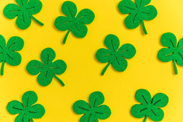 Simply minimal design with green shamrock clover leaves isolated on yellow background