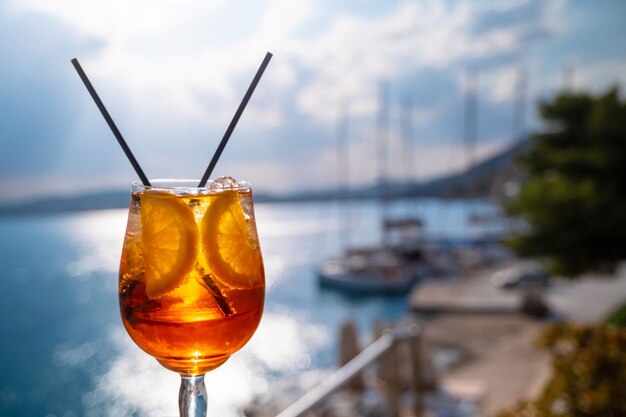 Sinaasappeldrankje of cocktail aan het tafeltje in het restaurant of café met zeeachtergrond