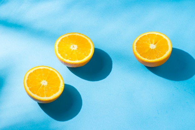 Sinaasappelen op een blauw oppervlak onder natuurlijk licht met schaduwen. Hard licht. Concept van voeding, gezond eten, rust in de tropen, vakantie en reizen, vitaminen.