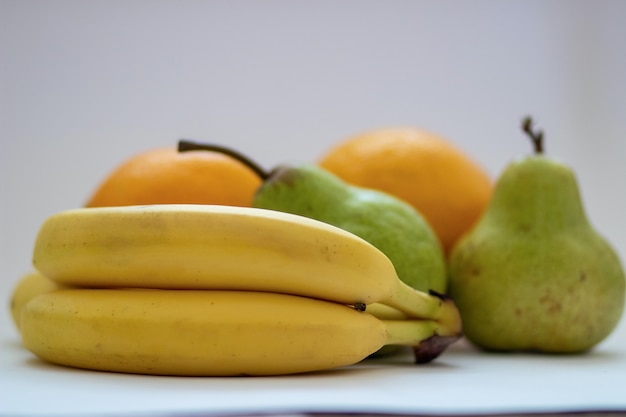 Sinaasappelen, peren en bananen op een witte geïsoleerde backgroun