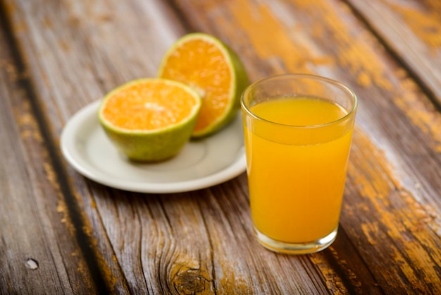 Sinaasappelsap. Glas op houten tafel met een gesneden sinaasappel op de achtergrond.