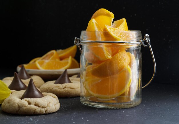 Sinaasappelschijfjes in glazen pot en koekjes op donkere achtergrond Gezond woonconcept Hoge kwaliteit foto