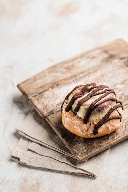 Булочка Синабон с шоколадом на деревянной доске с салфеткой на светлом фоне. Американская классическая булочка.