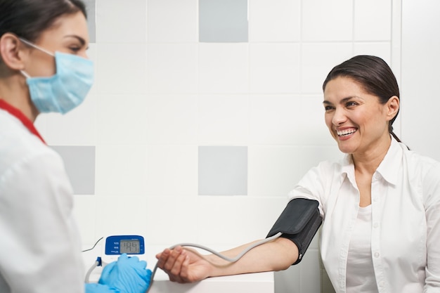 Sincere emotions. Attractive young female person keeping her arm on table while measuring blood pressure