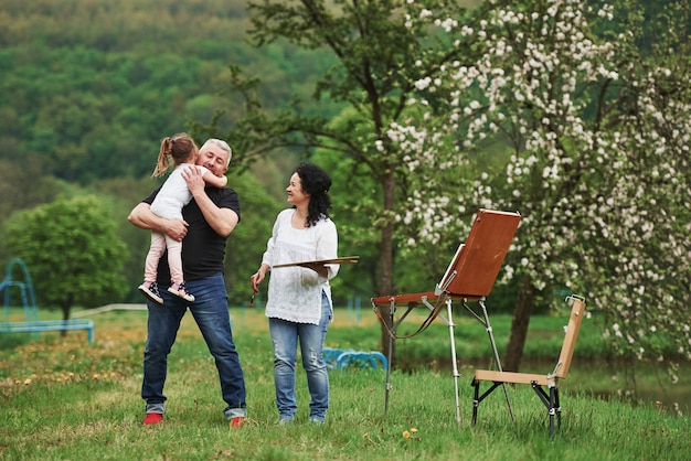 Sincere emotions. Grandmother and grandfather have fun outdoors with granddaughter. Painting conception