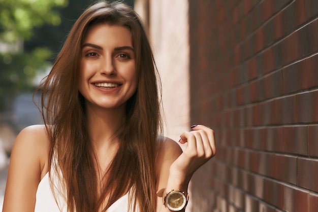 Sincere smile beautiful girl posing near brick background