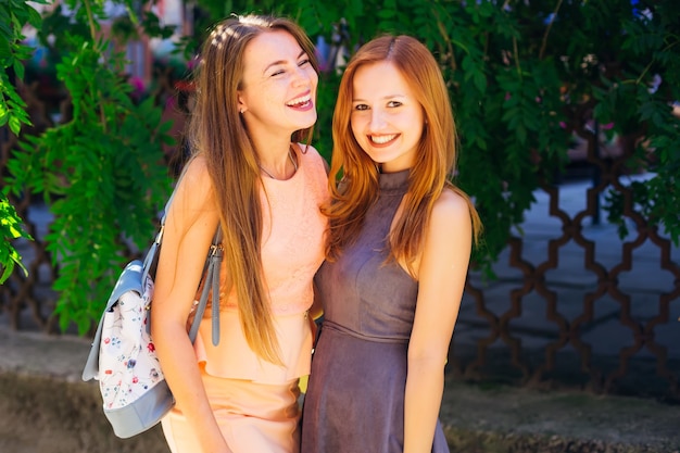 Sincere smiles of the best friends who have fun time. Close-up of girls in beautiful dresses