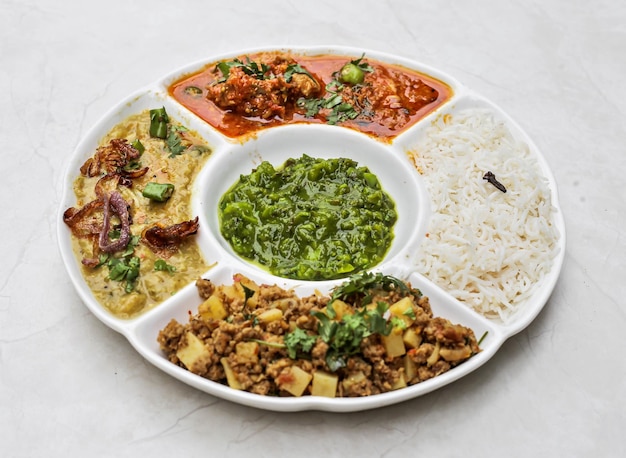 Синдхи неовощные тали с курицей алоо кима, корма, карри, пакора, рис и чатни, которые подаются в тарелке, изолированной на столе, с видом на индийские и пакистанские острые блюда