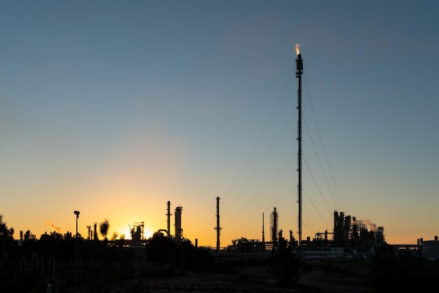 Sines refinery, Portugal at sunset with chimneys giving off flames and smoke