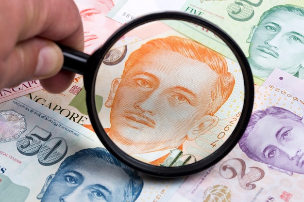 Singapore dollar in a magnifying glass a business background