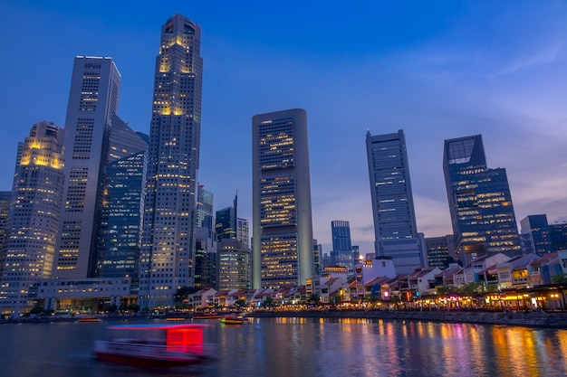 Singapore. Kade met cafés en wolkenkrabbers. Pleziervaartuigen. Schemering