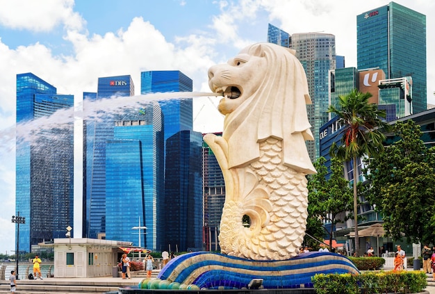 Foto singapore, singapore - 1 maart 2016: merlion-standbeeld dat het water uit zijn mond spuit in merlion park in downtown core van singapore in marina bay. wolkenkrabbers op de achtergrond.