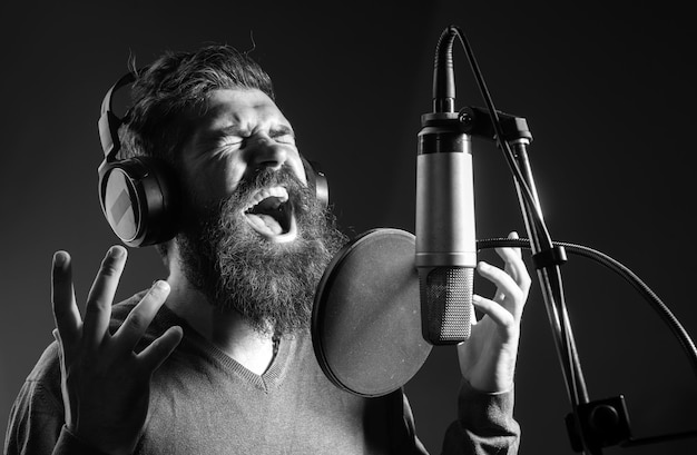 Foto l'uomo cantante che indossa le cuffie sta eseguendo una canzone con un microfono mentre registra in una musica