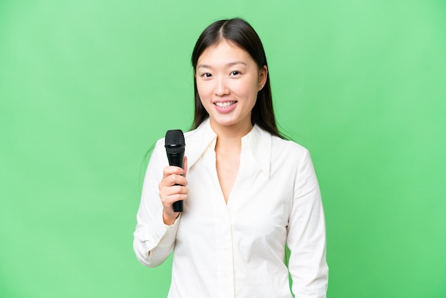 Singer picking up a microphone over isolated chroma key background smiling a lot
