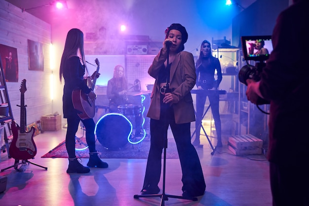 Singer singing in microphone and performing with her music band in the night club