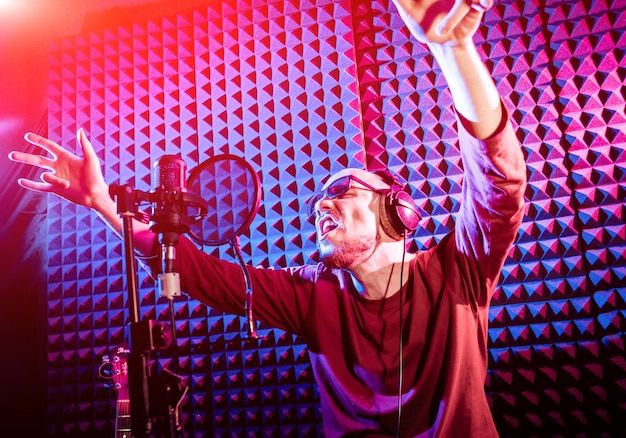 Photo the singer sings with a microphone in the recording studio.