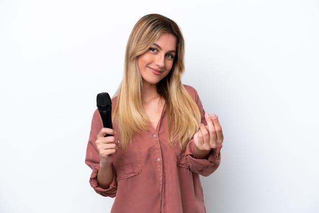 Cantante donna uruguaiana che prende un microfono isolato su sfondo bianco facendo un gesto di denaro