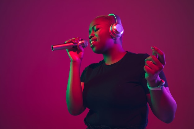 Singing in headphones Africanamerican young womans portrait on purple background