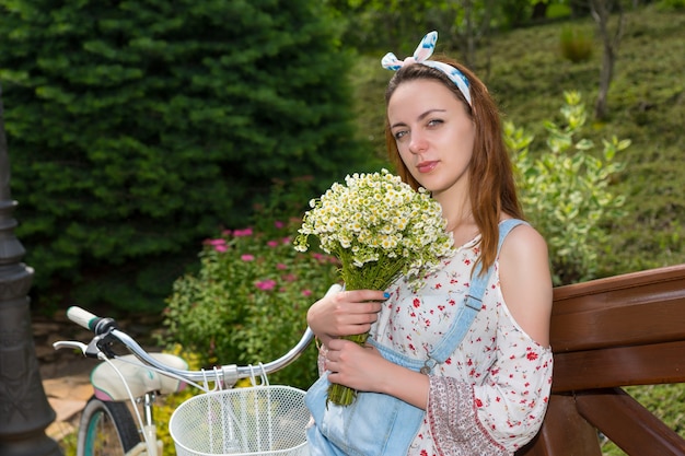 外の橋の手すりに寄りかかっている間小さな白い花の大きな花束を持つ単一の美しい若い女性