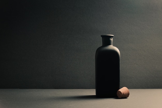 Single black ceramic bottle with the plug off over a dark background