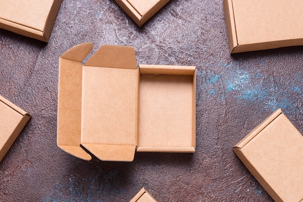 Single brown cardboard box opened, with cover on dark background