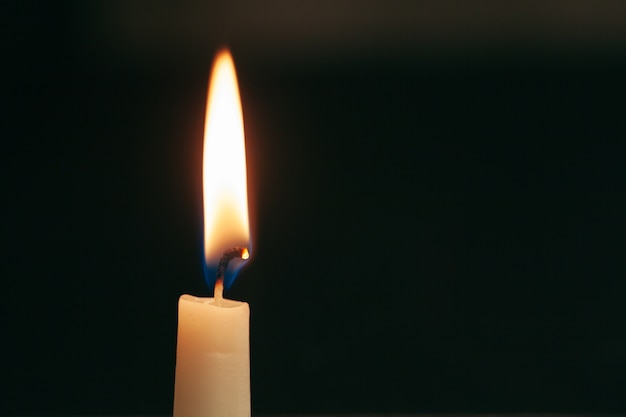 A single burning candle isolated with black background