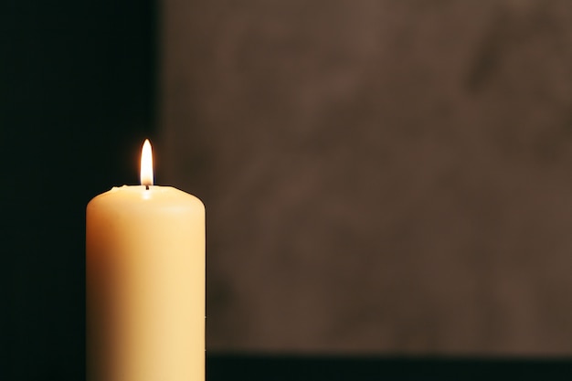 A single burning candle isolated with black