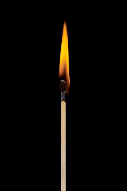 Photo a single burning match with the flame rising up isolated on a black background