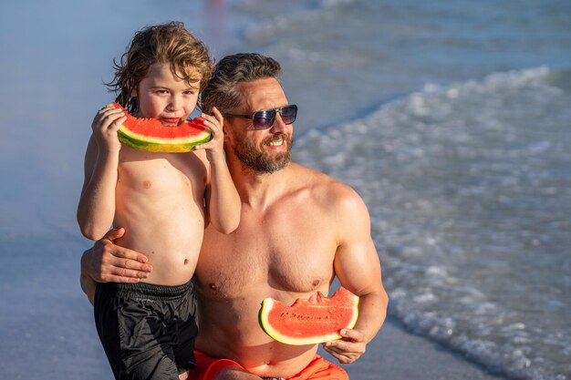 シングルパパと息子がビーチで育児 パパと息子は海でクオリティタイムを楽しんでいます パパと子供はバターメロンを食べています 健康的な食事 パパと子は育児休暇です 夏休み