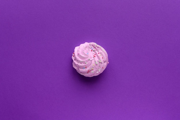 Single delicious purple meringues on purple background copy space