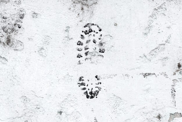 Foto una singola impronta di stivale sporca su un close-up di una parete di cemento bianco