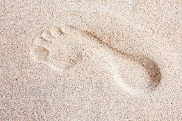 A single foot print imprinted in the sand on the beach, top view.