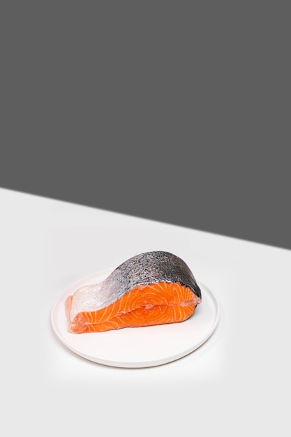 Single fresh raw salmon steak on the edge of white table creative minimalist mockup with copy space