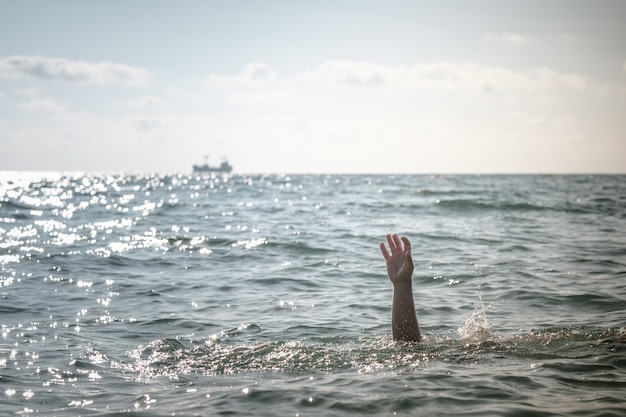 Одна рука тонущего человека в море с просьбой о помощи. торчать из воды