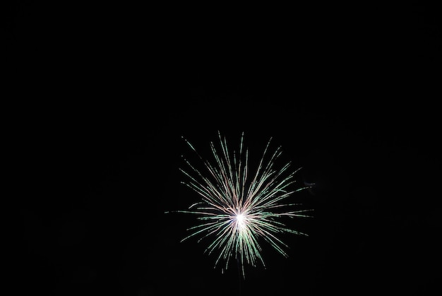 Single high green explosion at a fireworks display on new years eve night