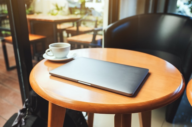 Un singolo computer portatile con una tazza di caffè sul tavolo di legno