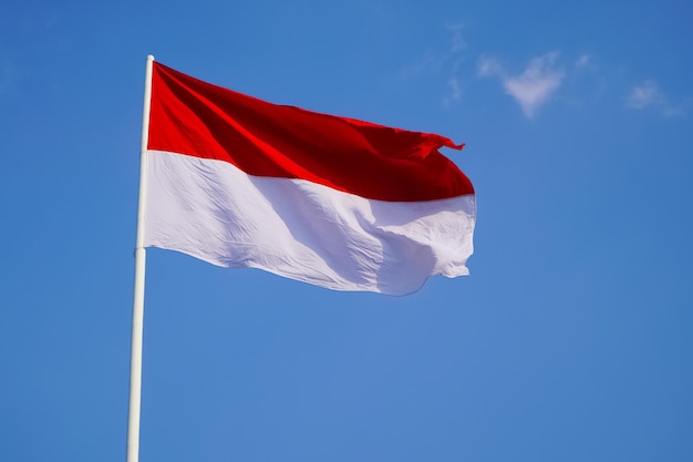 The single large red and white indonesian flag flutters in the strong wind ahead  independence day