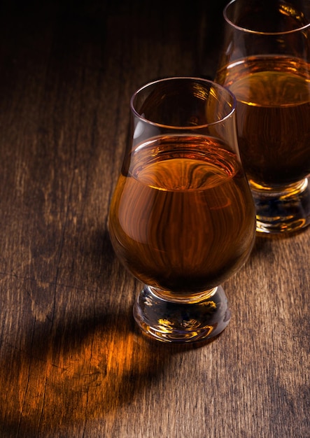 Single malt scotch whiskey in glencairn glasses on wooden table background Top view