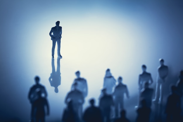 Photo single man standing in front of group of people.